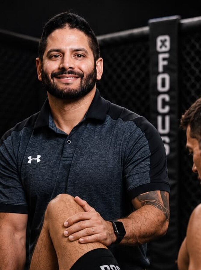 Dr. Rob Ninan, PT, DPT, working with an athlete inside an MMA cage.